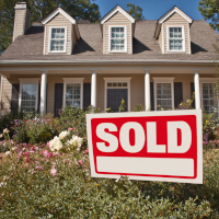 a beautiful home with a red sold sign on the front yard