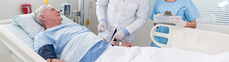 older man laying in a hospital bed talking to a doctor and nurse