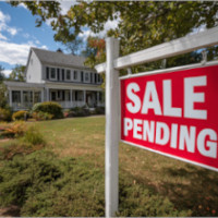 an image of a two-storey house with a red "sale pending" sign on the foreground