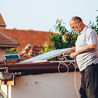 elderly man installing solar panel