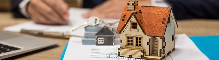 miniature house with man signing documents in background