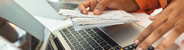 Person using calculator with receipts on one hand