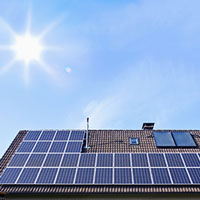 solar panels on houseroof in front of blue sky with sun