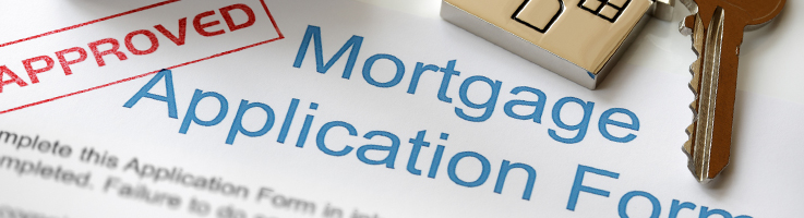 house key on top of mortgage loan application stamped with 'approved'