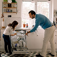 father and daughter putting dishes in dishwasher
