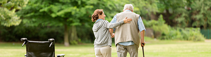 caregiver helping a senior man walk