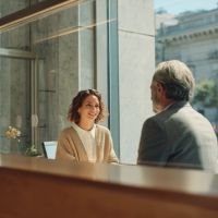 a woman smiling while talking to an older male representative in front of her