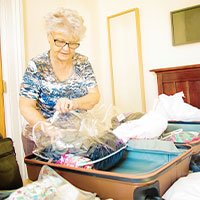 lady putting clothes from luggage into large plastic bag