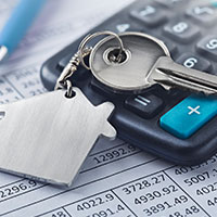 house key on top of a calculator and mortgage document
