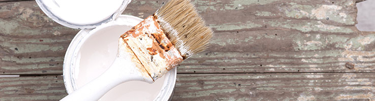 paint brush laying on top of an open paint can