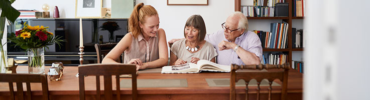 mature woman with her parents looking at a photo album at home