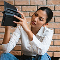 woman worriedly checking near empty wallet