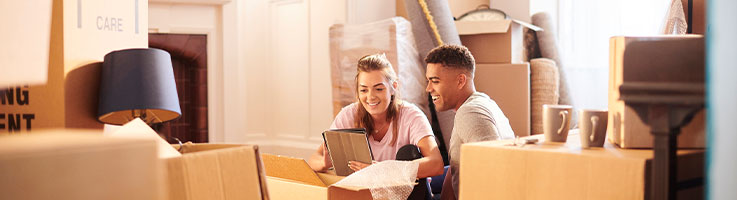 couple using tablet with moving boxes around them