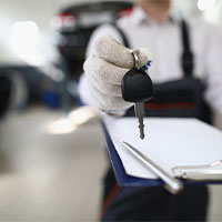 auto mechanic holding a checklist and handing car keys