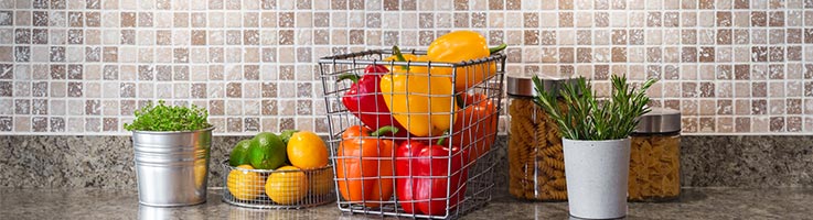 fruit in baskets in front of a tile backsplash