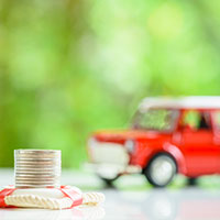 stacked coin in front of red land rover toy car