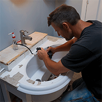 Guy fixing a broken faucet and sink