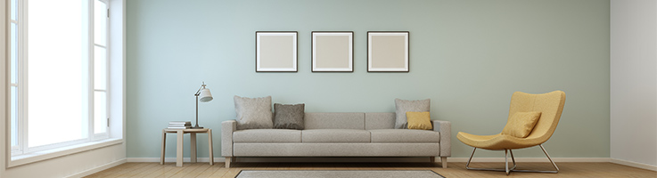 light blue living room with three pictures hung above a gray couch