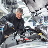 auto mechanic checking engine oil