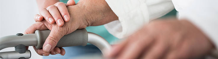 older woman using a walker with help from a nurse