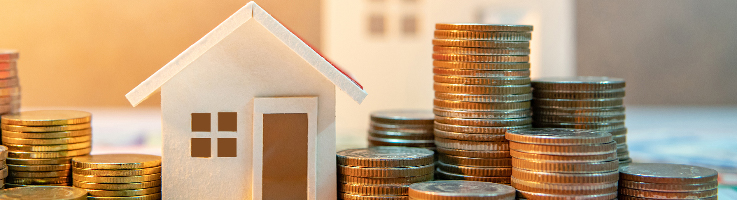 model home next to stacked coins