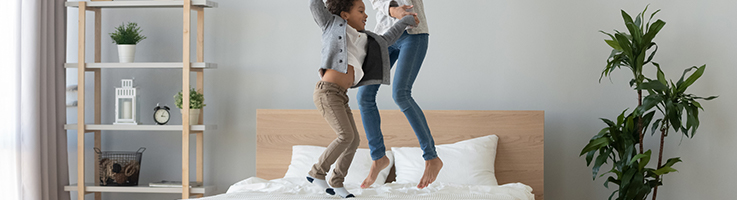 mom and son jumping on bed