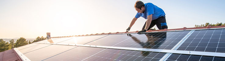 worker installing solar panels on roof