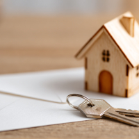 wood model house and keys on top of a letter envelope