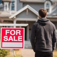 a man standing in front of a house for sale