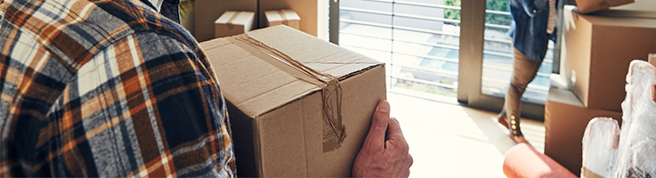 man moving box into house