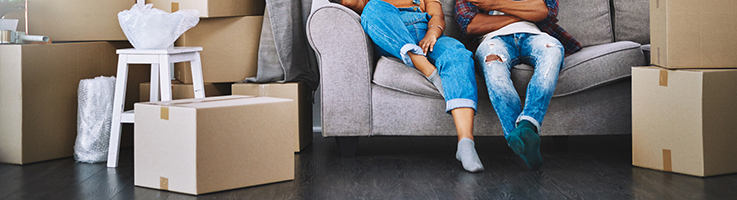 couple sitting on couch with moving boxes