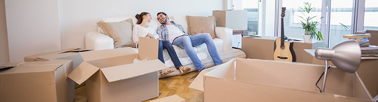 couple sitting on a couch surrounded by moving boxes