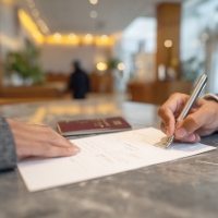 someone signing a document, with a passbook beside it