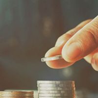 hand placing a coin on top of a stack