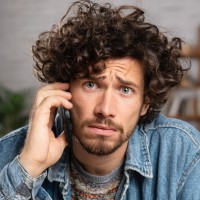 a guy holding a phone over his ear looking concerned