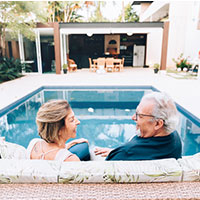 happy couple with swimming pool in background smiling talking with loan officer