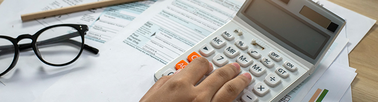 accountant's hand calculating taxes with calculator