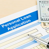 Personal loan application paper, pen and money on top of a table