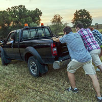 a group of guys helping to push-start a pickup truck