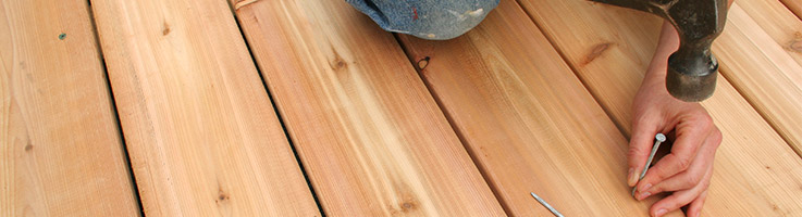 man hammering nails into a deck