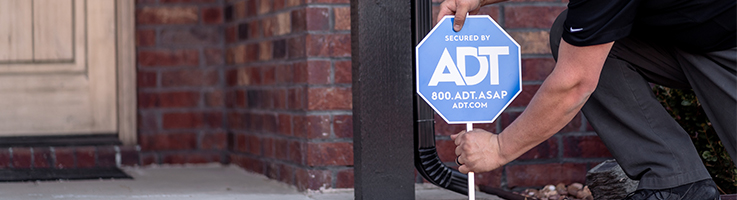 man inserting adt sign in front of home
