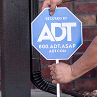 man inserting adt sign in front of home