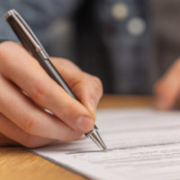 closeup of a hand holding a pen while writing on a piece of paper