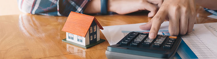 person computing with calculator and miniature house