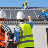 engineers installing solar panels on roof of a home