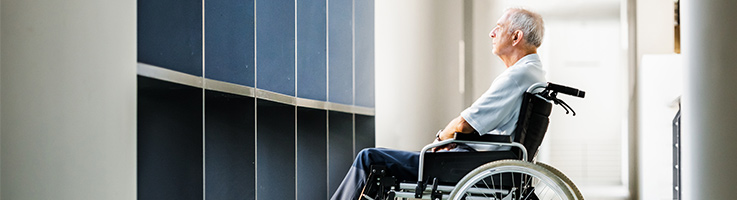 old man sitting in a wheelchair looking out a window