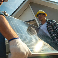 builders carrying a solar panel