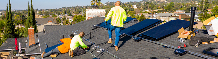 technicians installing solar panels on roof