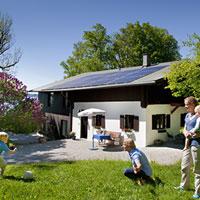 a family spending time in the yard and a house topped with solar panels in the background