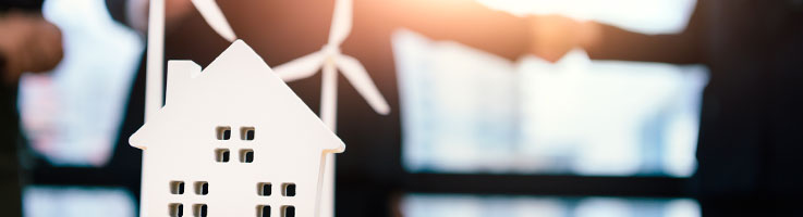 closeup of house and windmill props with business people doing handshake on the background